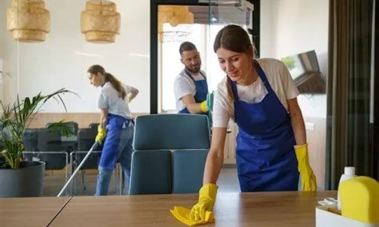 Petugas kebersihan profesional sedang membersihkan ruangan kantor